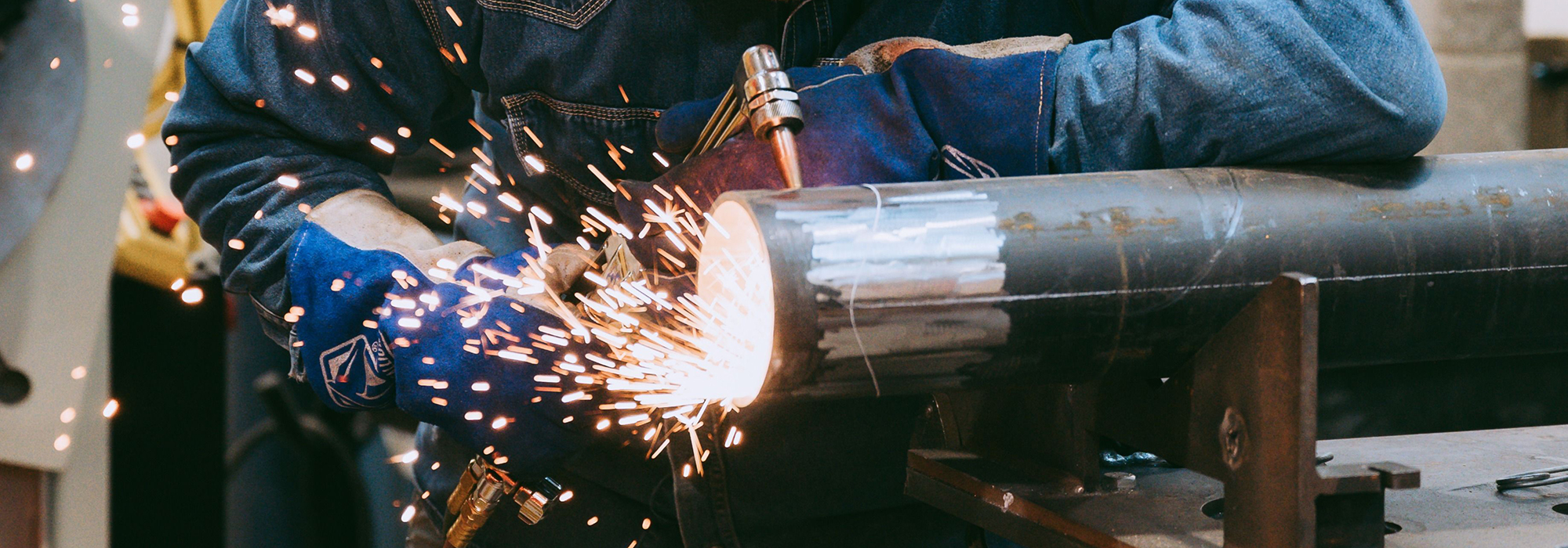 Pipefitter cutting a metal pipe with a torch