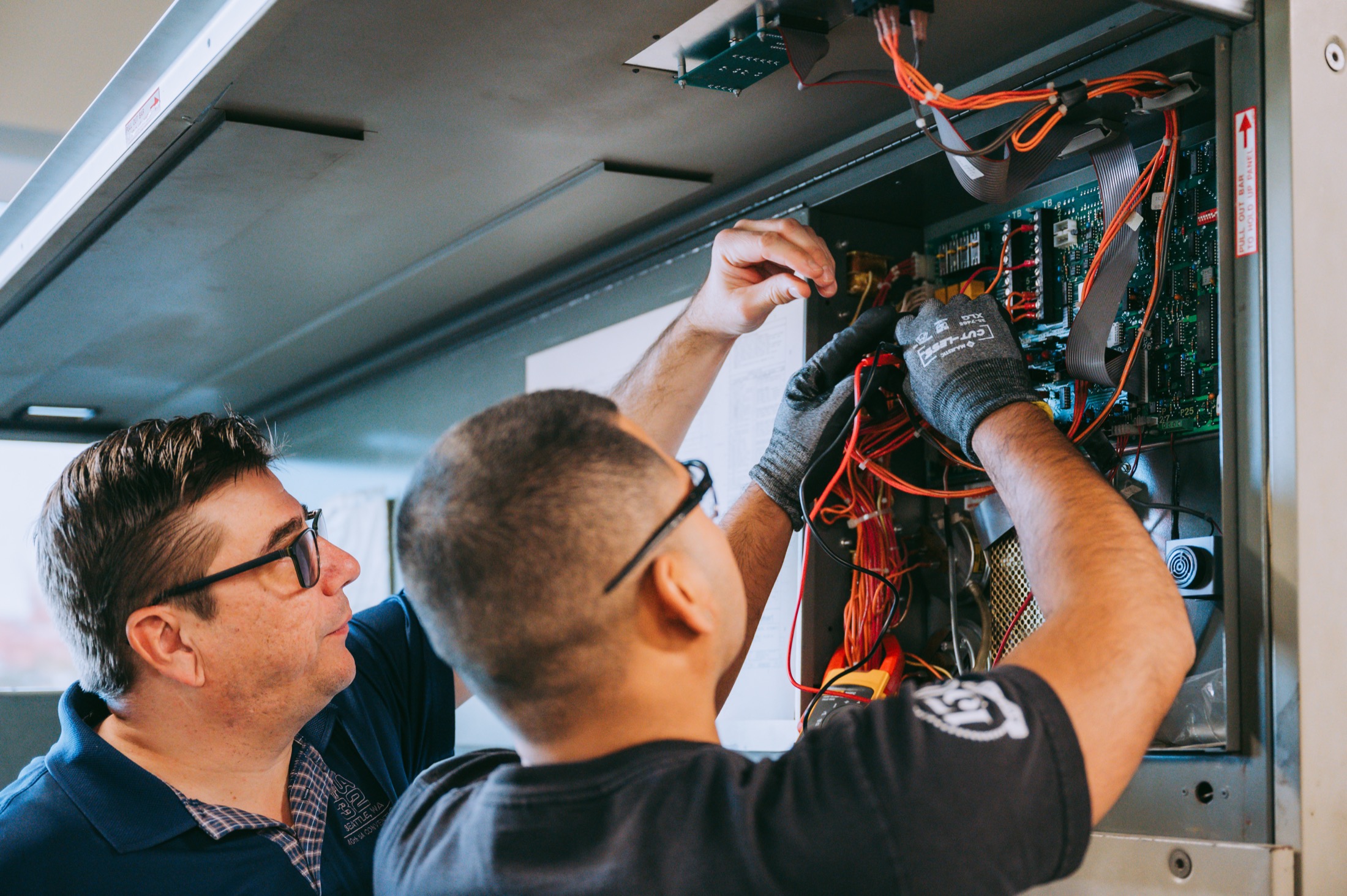Two men working on the wiring of a board